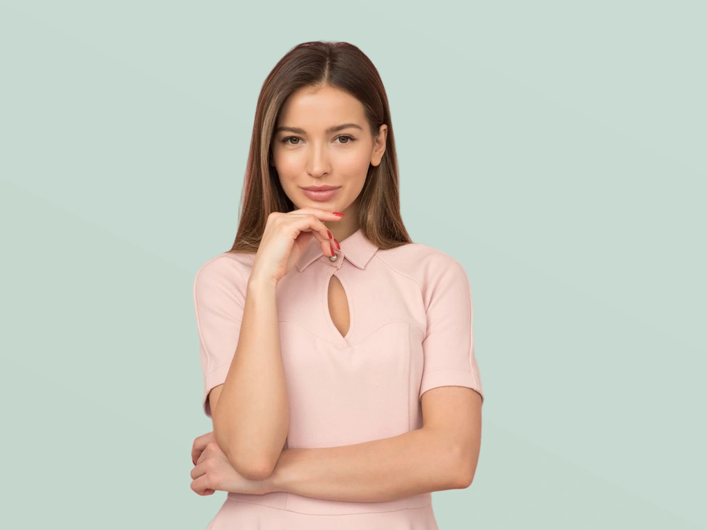 Woman with long brown hair in a pale pink collared blouse before